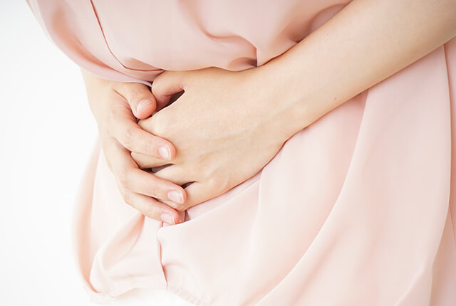 腹部を押さえている女性